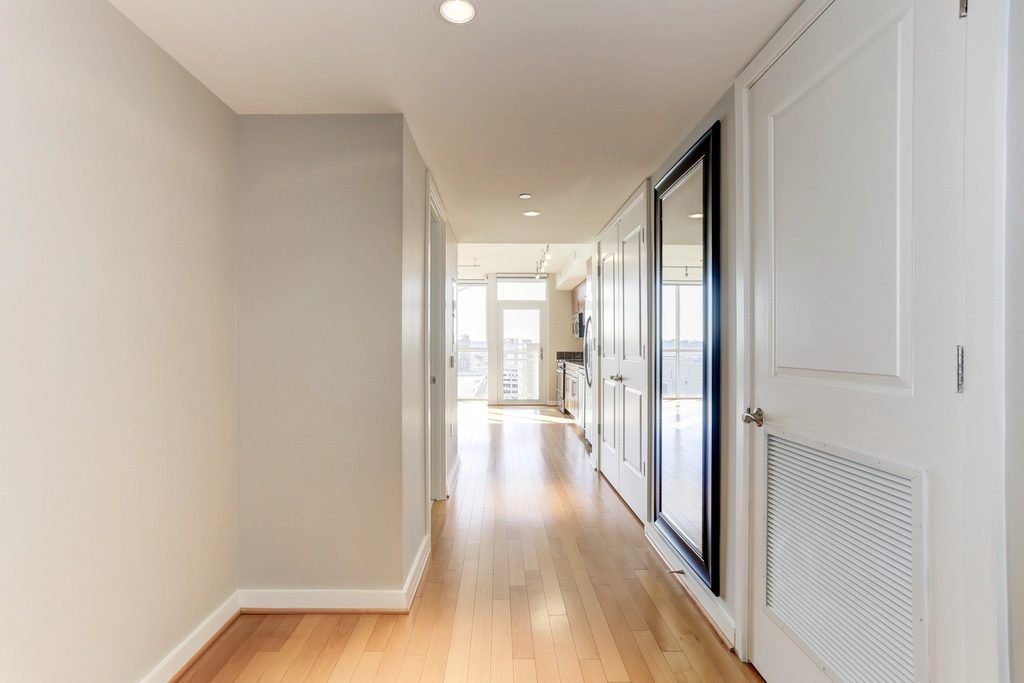 Bright residential corridor lined with flush white doors and a timber floor