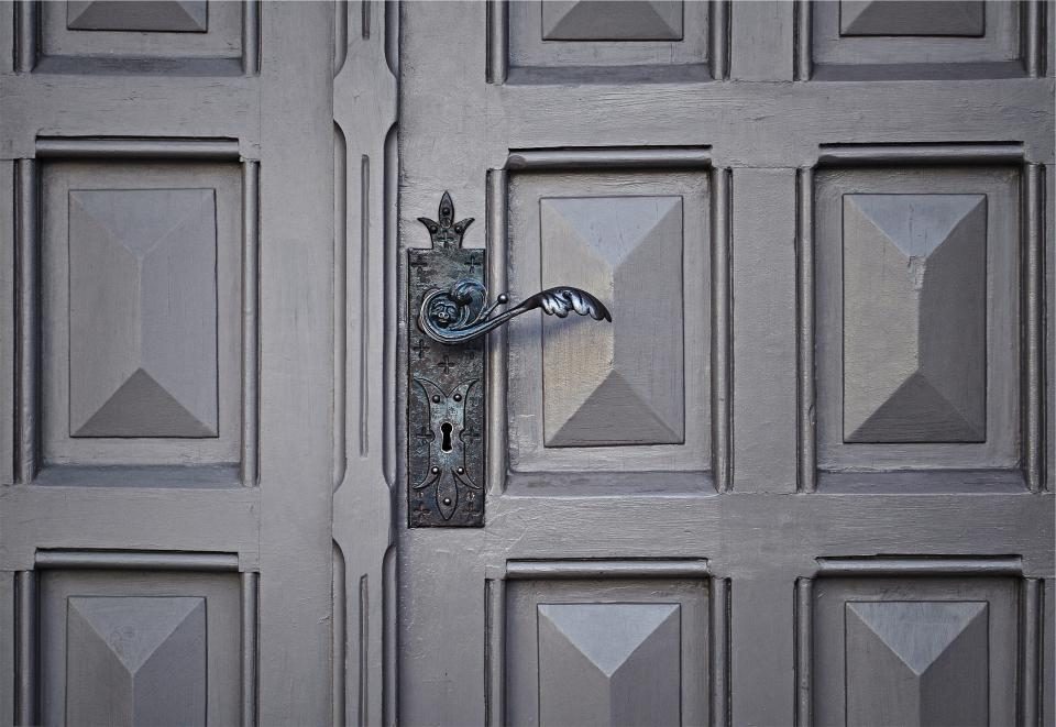 Lever handle and lock escutcheon mounted on a grey panelled door leaf