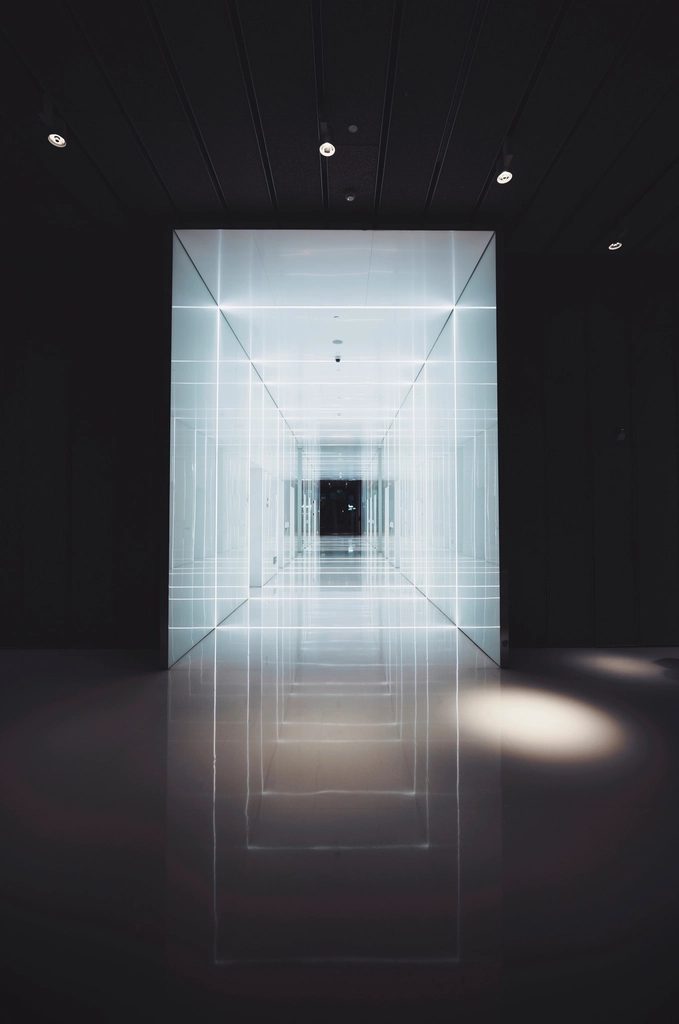 Dark interior corridor with a brightly lit rectangular door opening in perspective