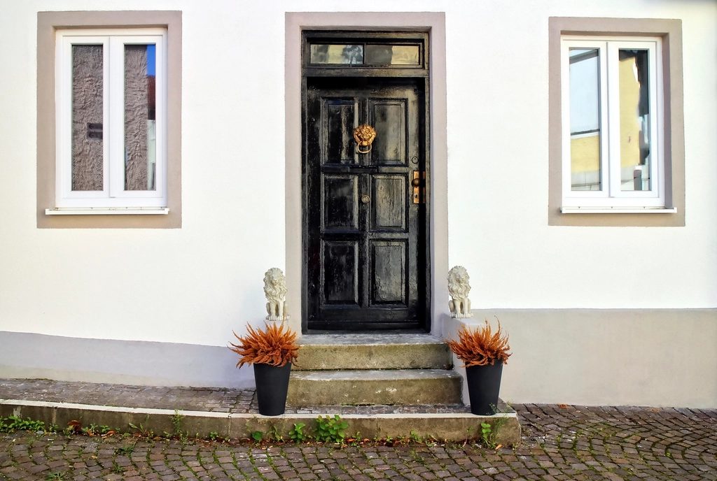 Black panelled entrance door in a pale rendered facade above a stone step