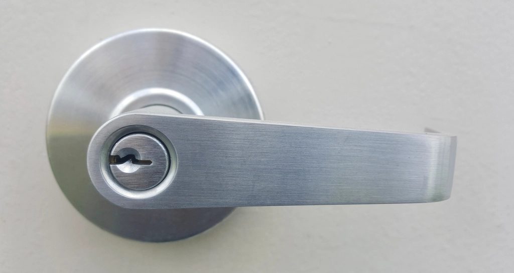 Brushed stainless lever handle and keyed cylinder on a white door leaf