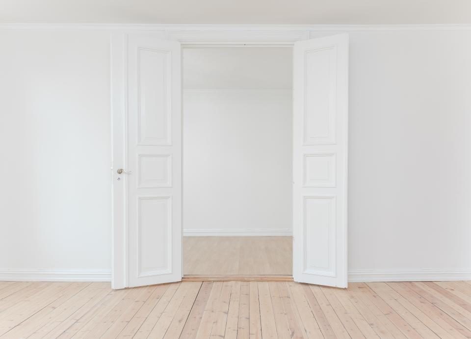 Pair of white double doors standing open into a bright empty room