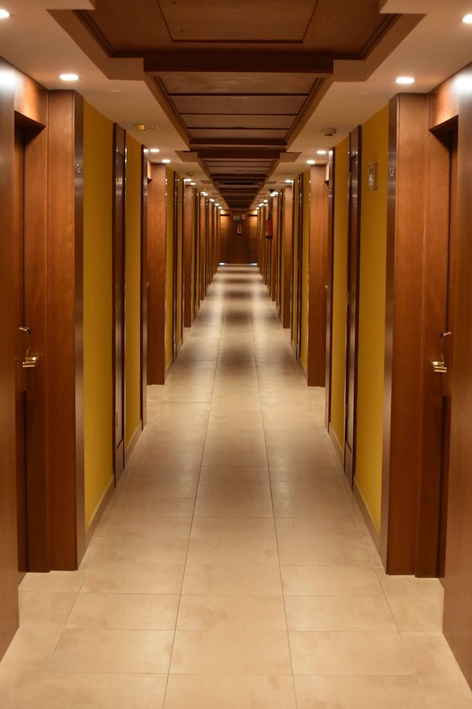 Hotel corridor in perspective lined with timber guestroom doors