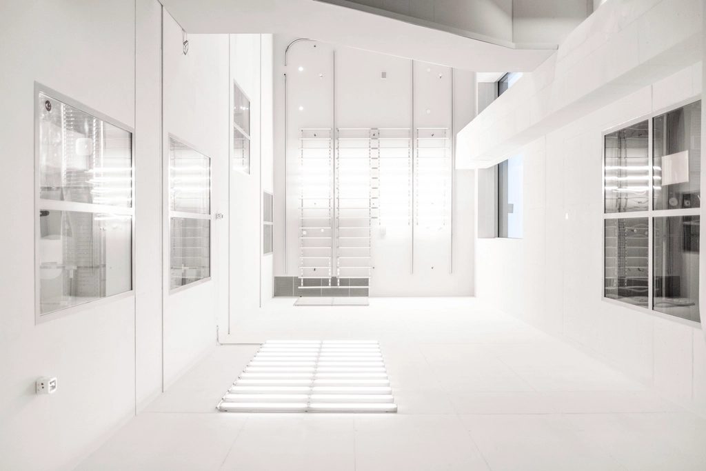 Bright white clinical corridor lined with glazed door openings and full-height frames