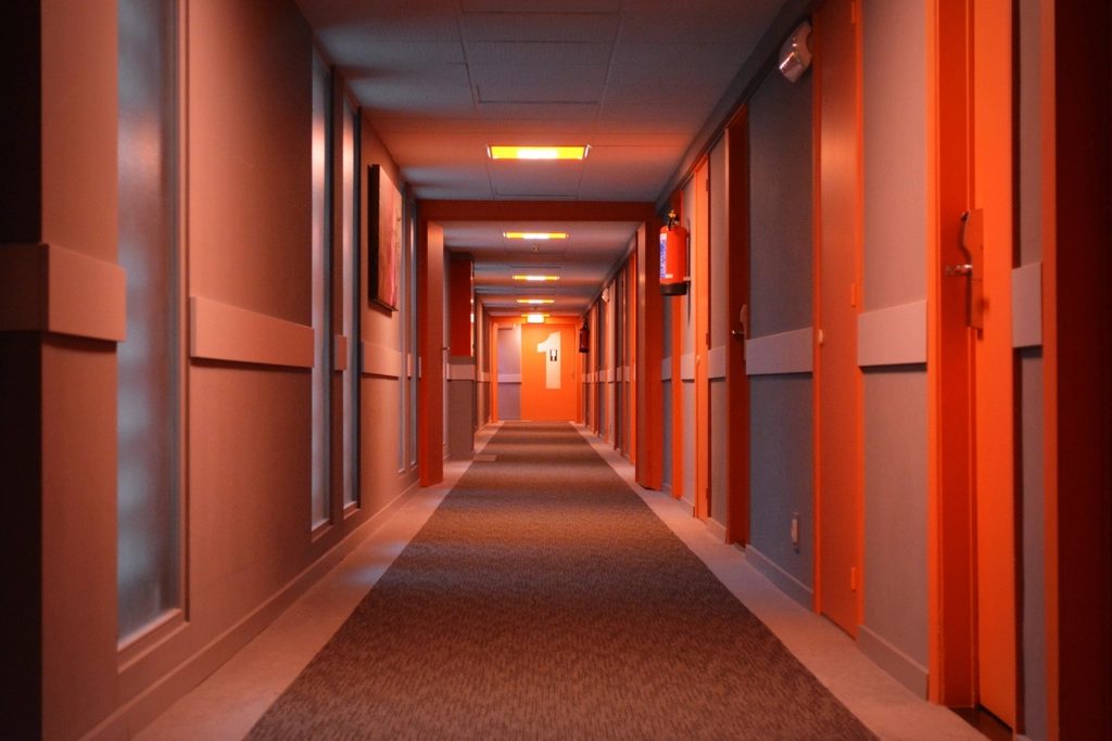Long hotel corridor with recessed guestroom doors and warm accent lighting